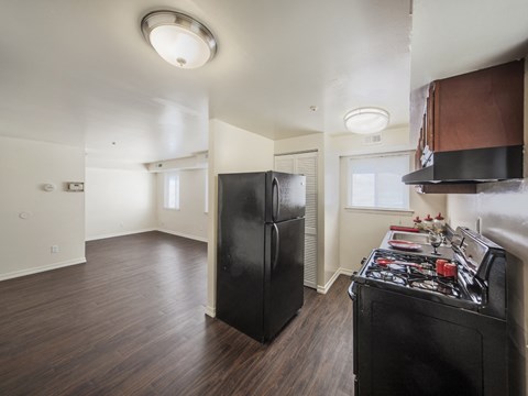 an empty kitchen and living room with a black refrigerator and stove